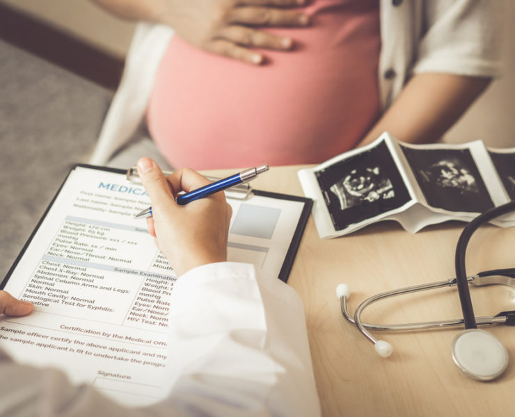 Doctor going through pre-birth maternity benefits with pregnant patient
