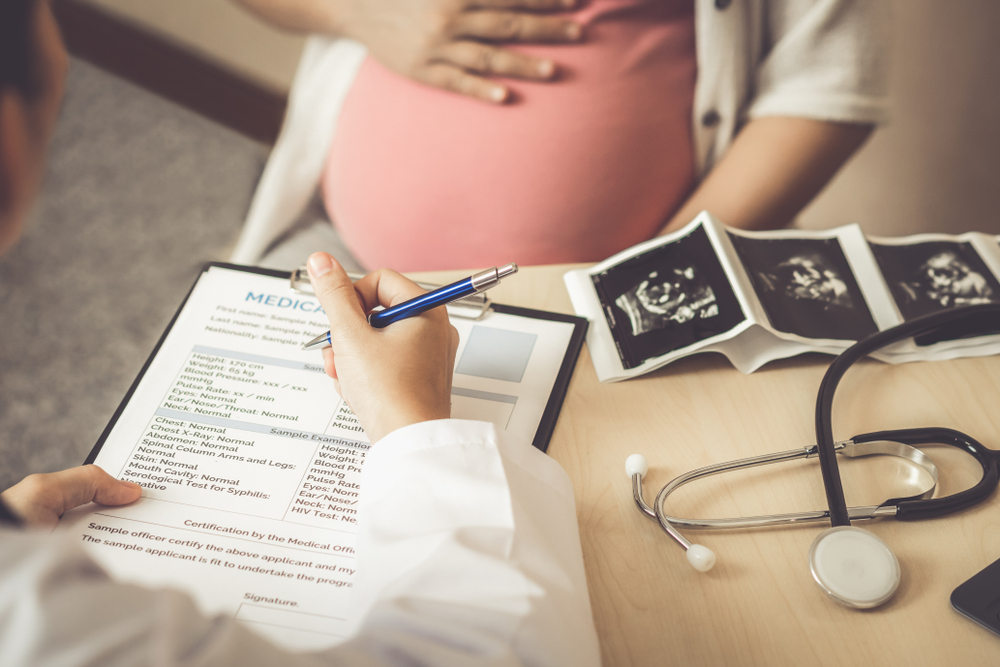 Doctor going through pre-birth maternity benefits with pregnant patient